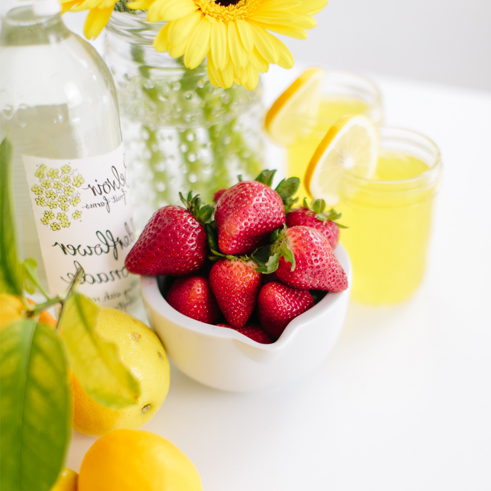 Ernährungspsychologie: Eine Schale mit Erdbeeren, Zitronen, zwei Gläser mit Zitronensaft und Zitronen.
